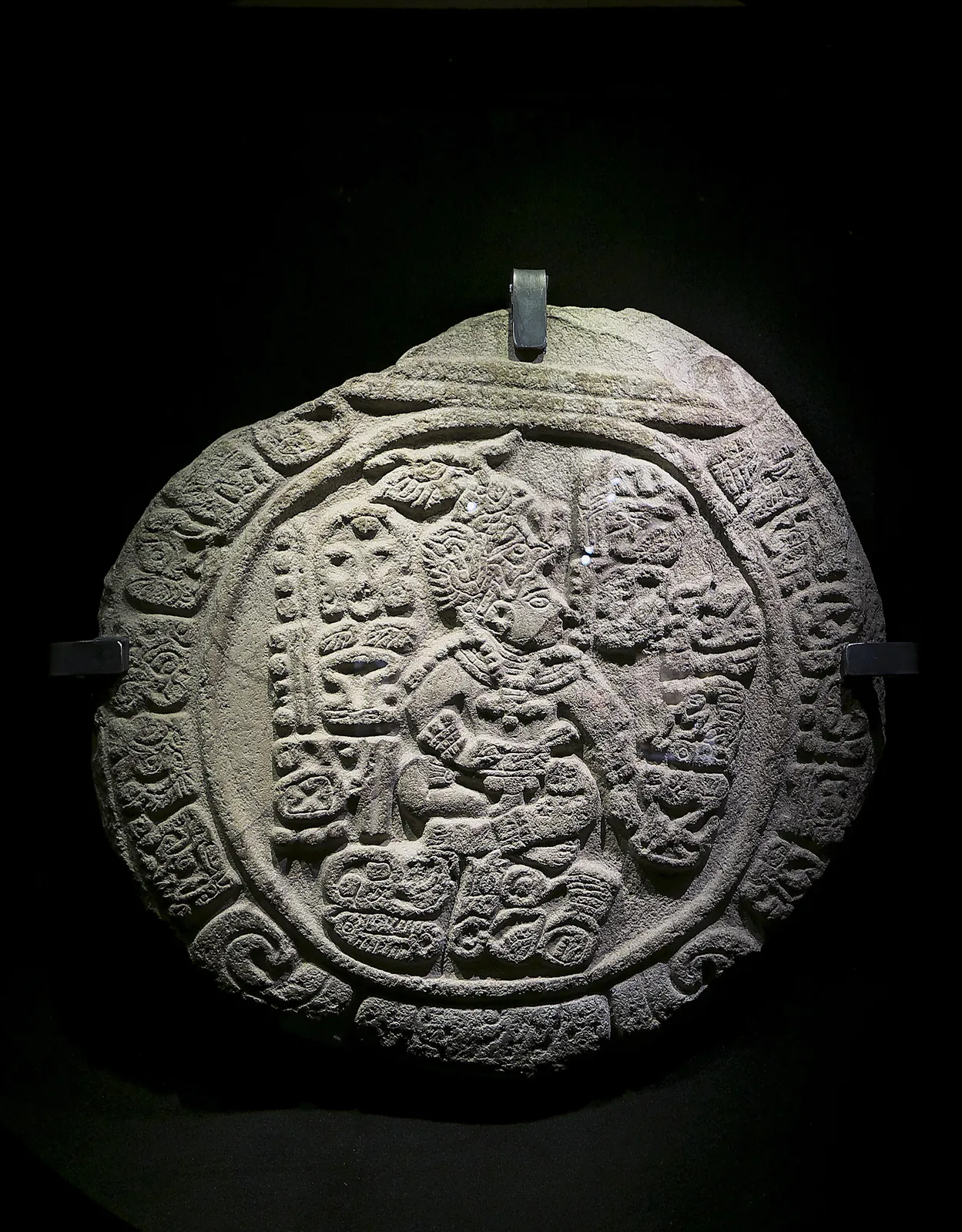 L'autel L de Quiriguá, bloc de pierre sombre sculpté d'une figure et de glyphes dans un cartouche circulaire